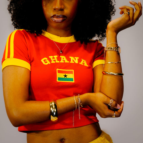 Person wearing a red 'Ghana' t-shirt with yellow accents and accessories.