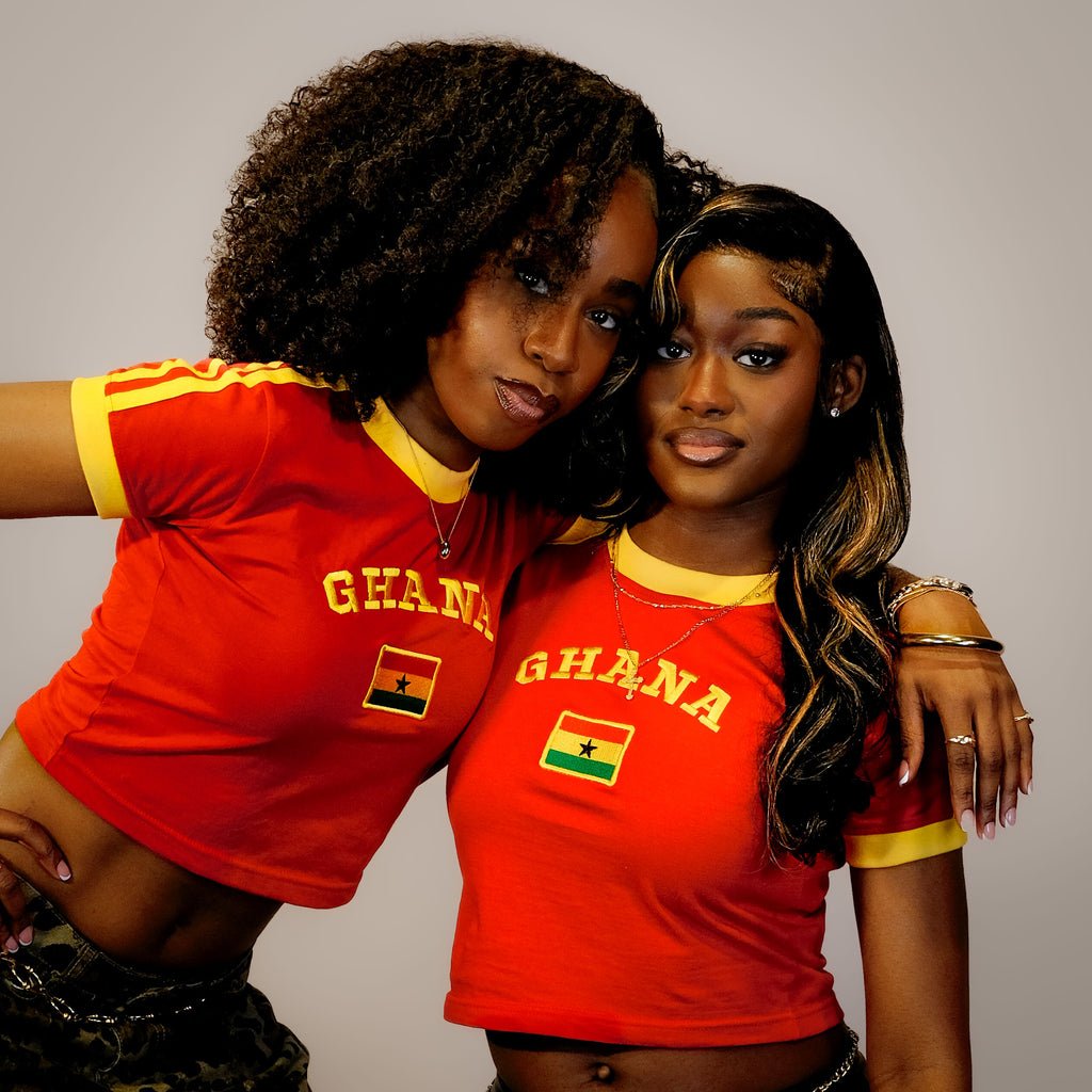 Two women wearing red 'Ghana' shirts with a flag design on a plain background